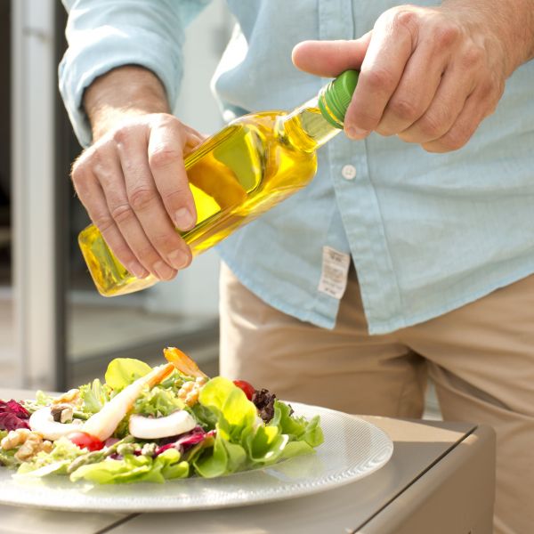 Oil Bottle in Hands above salad