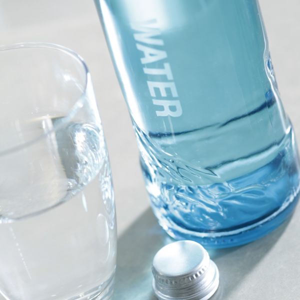 Water bottle and waterglass and screw top on table